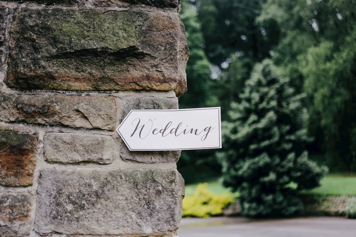 A stone pillar of a gate with a sign saying wedding